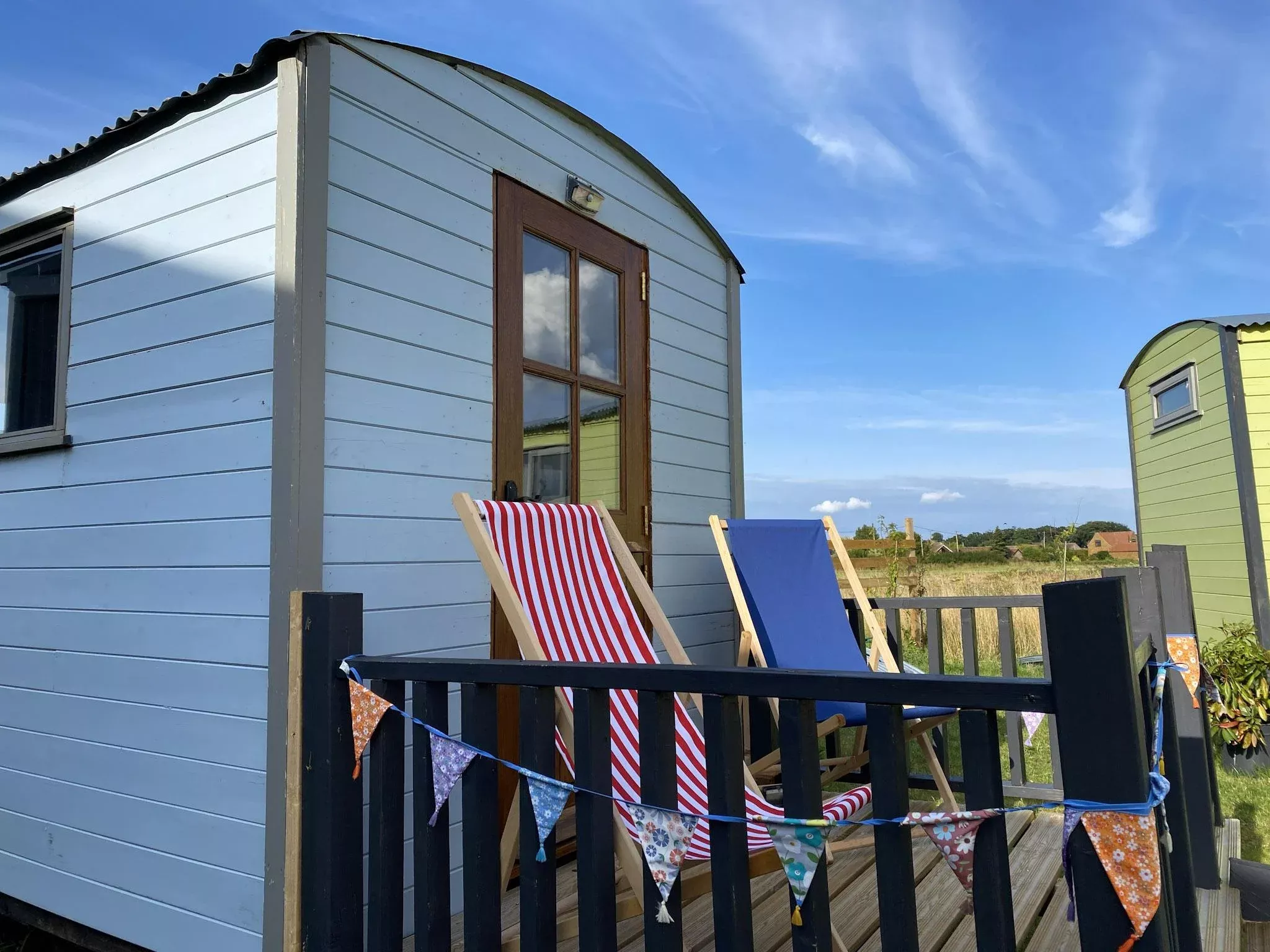 shepherds hut with two deck chairs under a beautiful blue sky