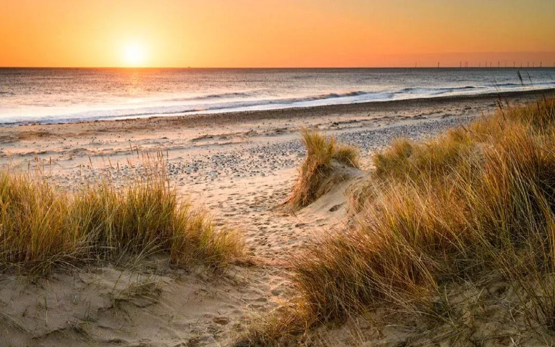  sunset over the sea with the sand and dunes in the forefront