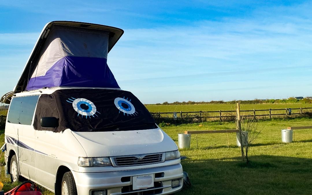 A campervan with eyes for a windshield, with views of the Norfolk meadows as seen from our campsite by the beach