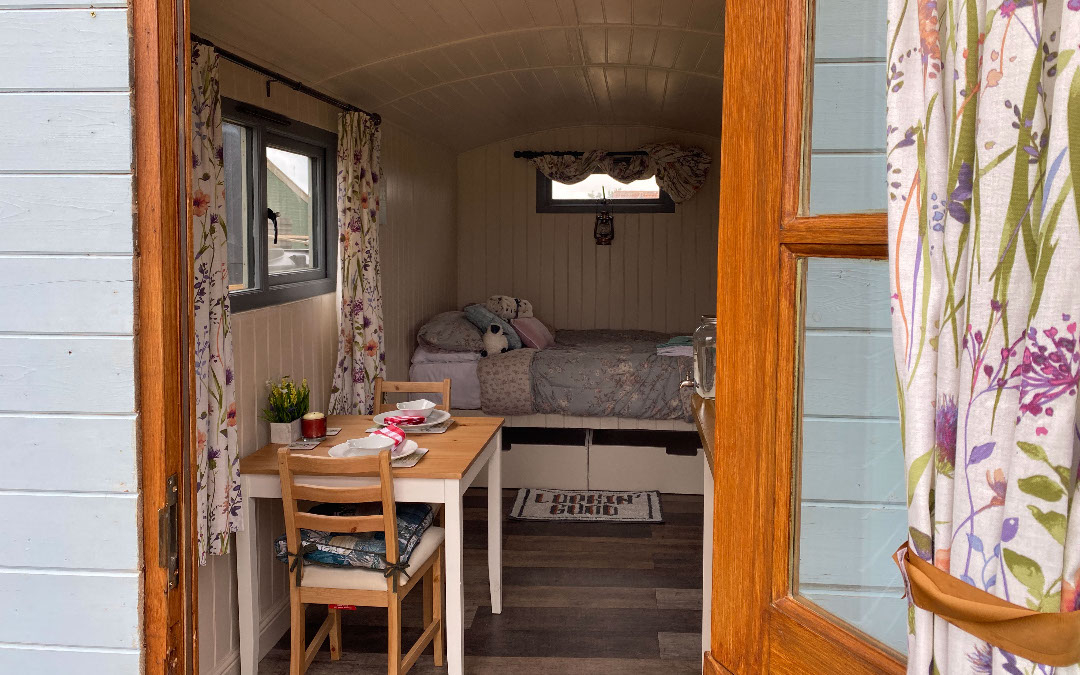 A view of the comfy double beds in our glamping shepherds huts, with bistro seating, perfect for couples