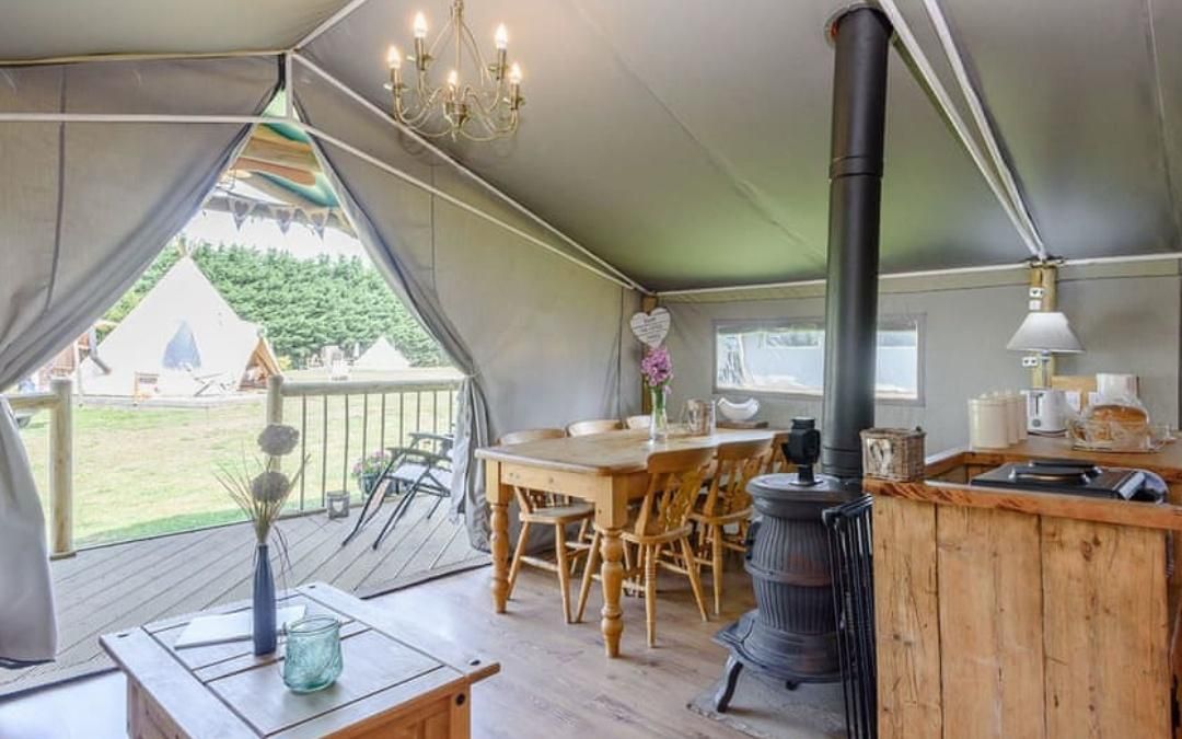 Safari tent interior with a dining table, coffee table, and a stove