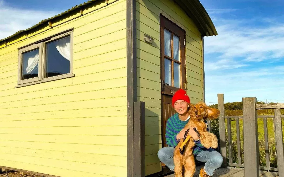 a person with their dog outside of a hunstanton shepherds hut