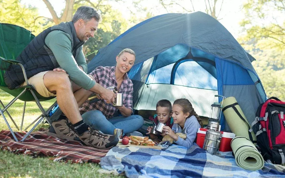 a family sat outside the tent enjoying a picnic