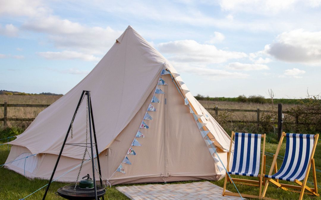 glamping bell tent with deck chairs and a bbq outside and an open field in the background