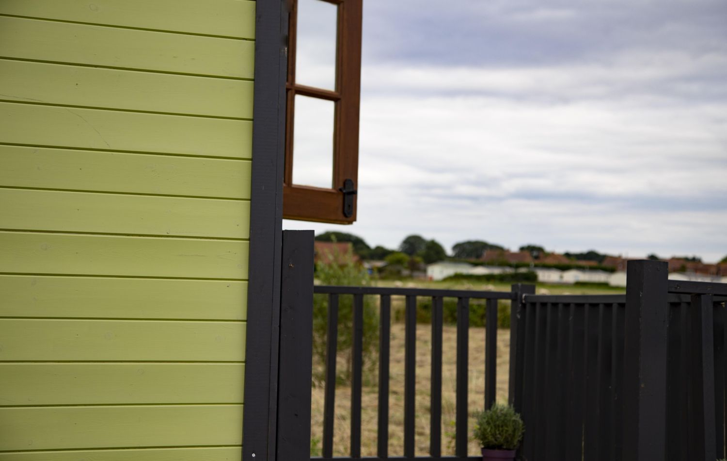 side of shepherds hut with an open window looking out on a field