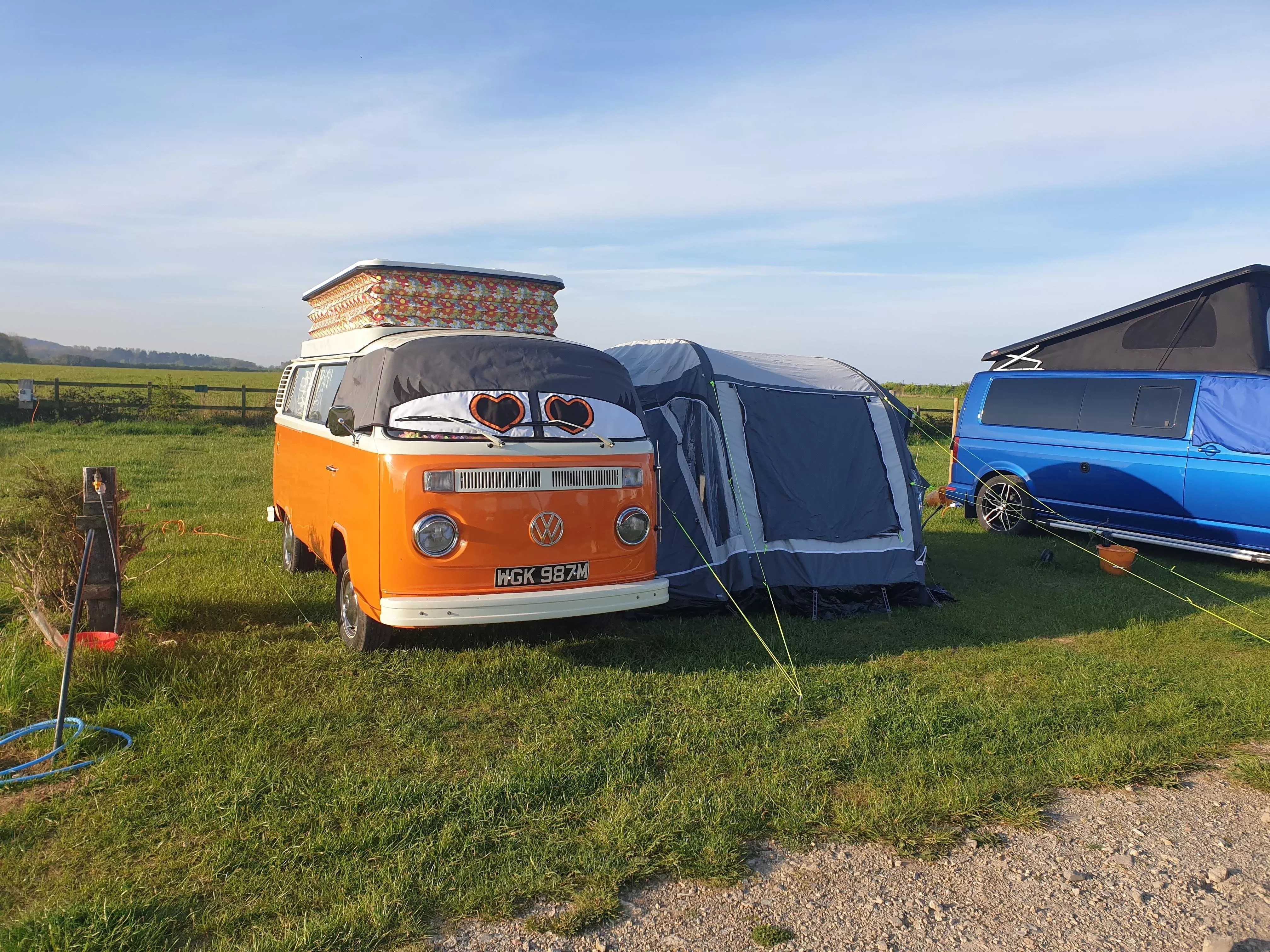 an orange vw campervan with eyes and an awning