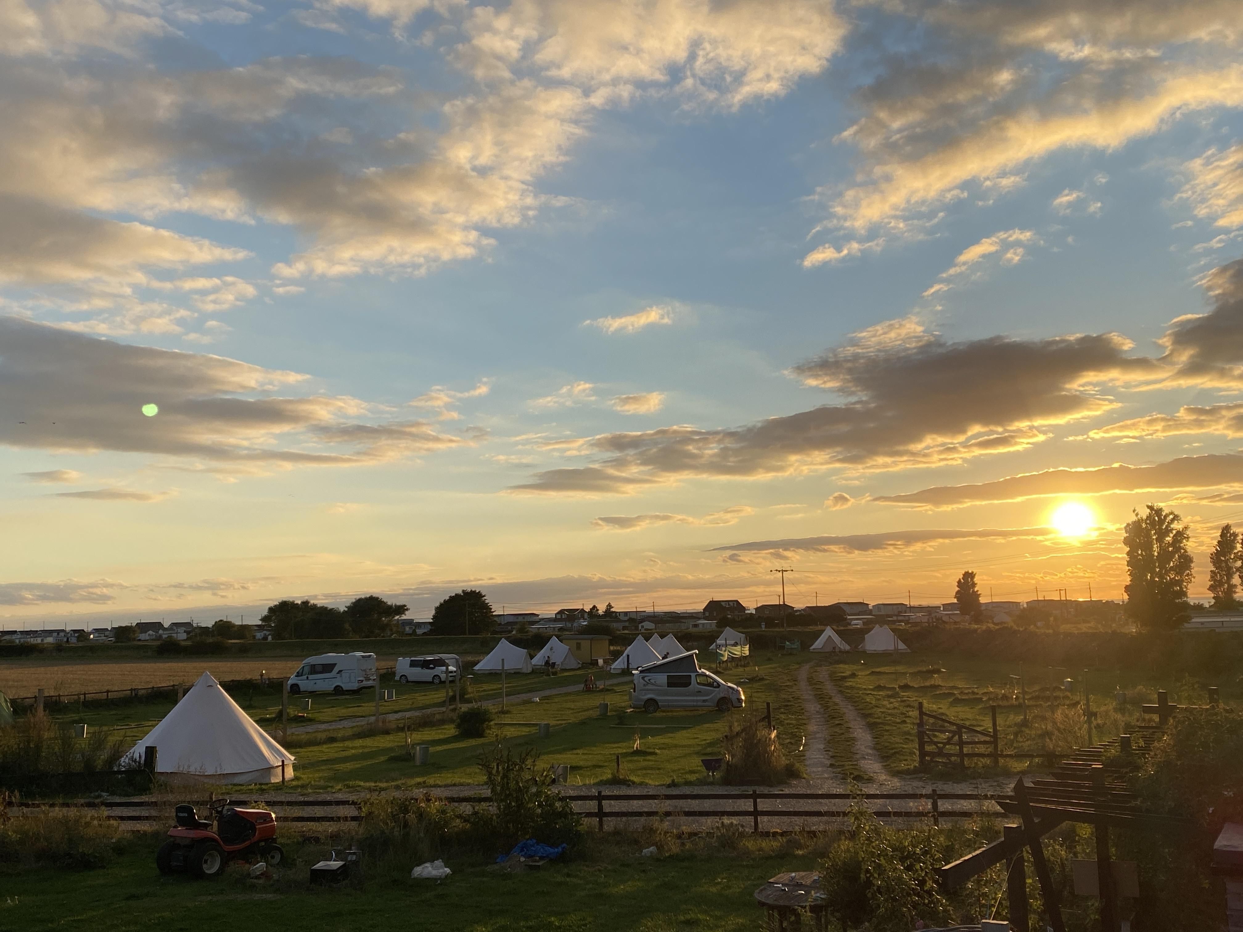 Why go Camping in Hunstanton? A hunstanton campsite with the sun setting in the background with a beautiful blue sky