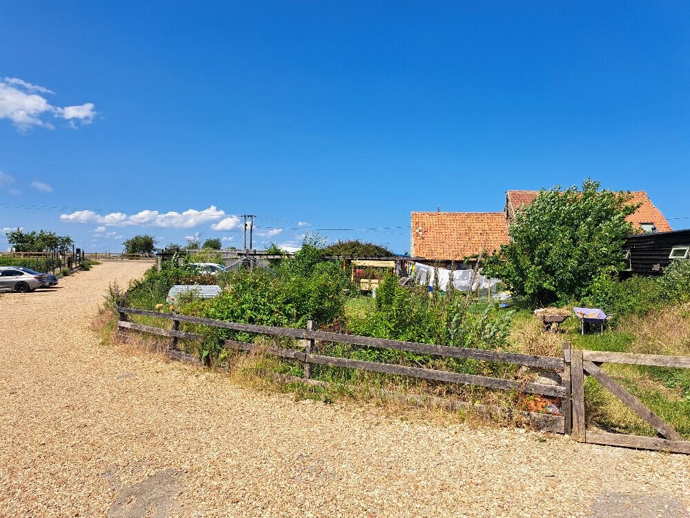 A restored, well-kept garden with gravel path and repaired buildings in the back