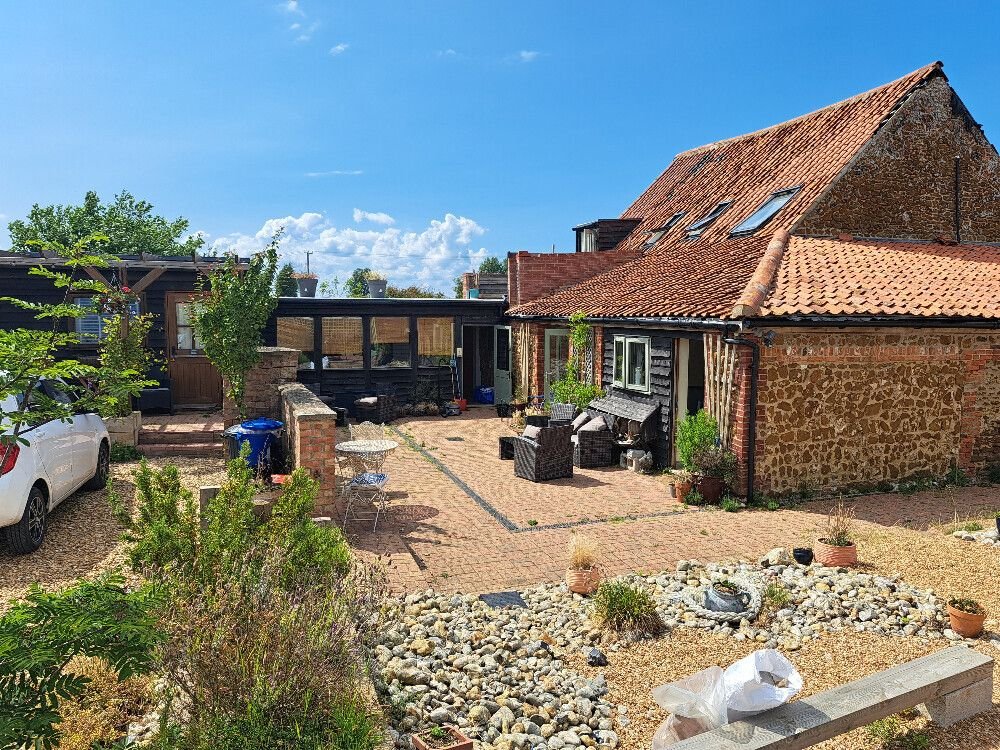 Fully restored farm buildings with re-tiled roofs, clean wood panelling, tiled floors, and lush plants